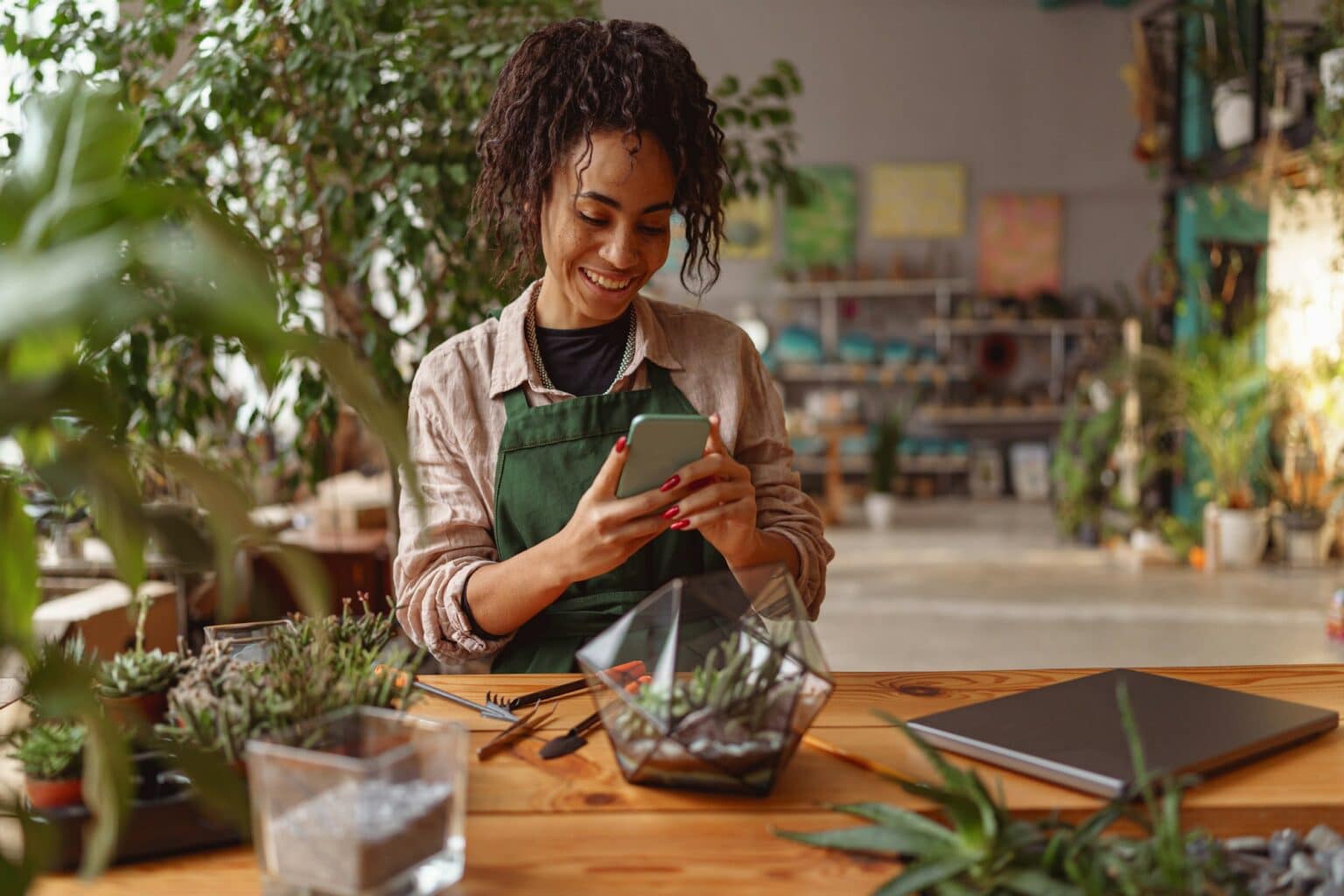 Smiling woman florist taking picture with her plants for publishing in social media